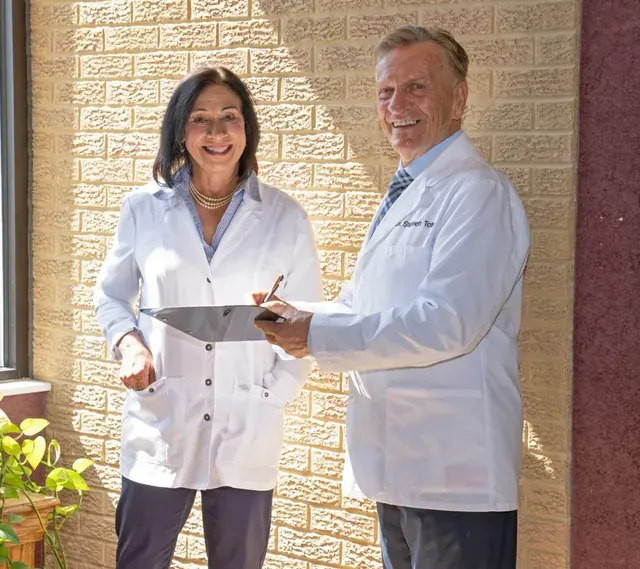 Dr. Toth and Sheree Toth reviewing a patient chart by the office window